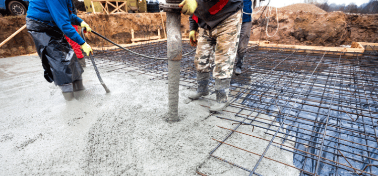 Man pouring a slab from a concrete truck and using a concrete vibrator to remove air bubbles.
